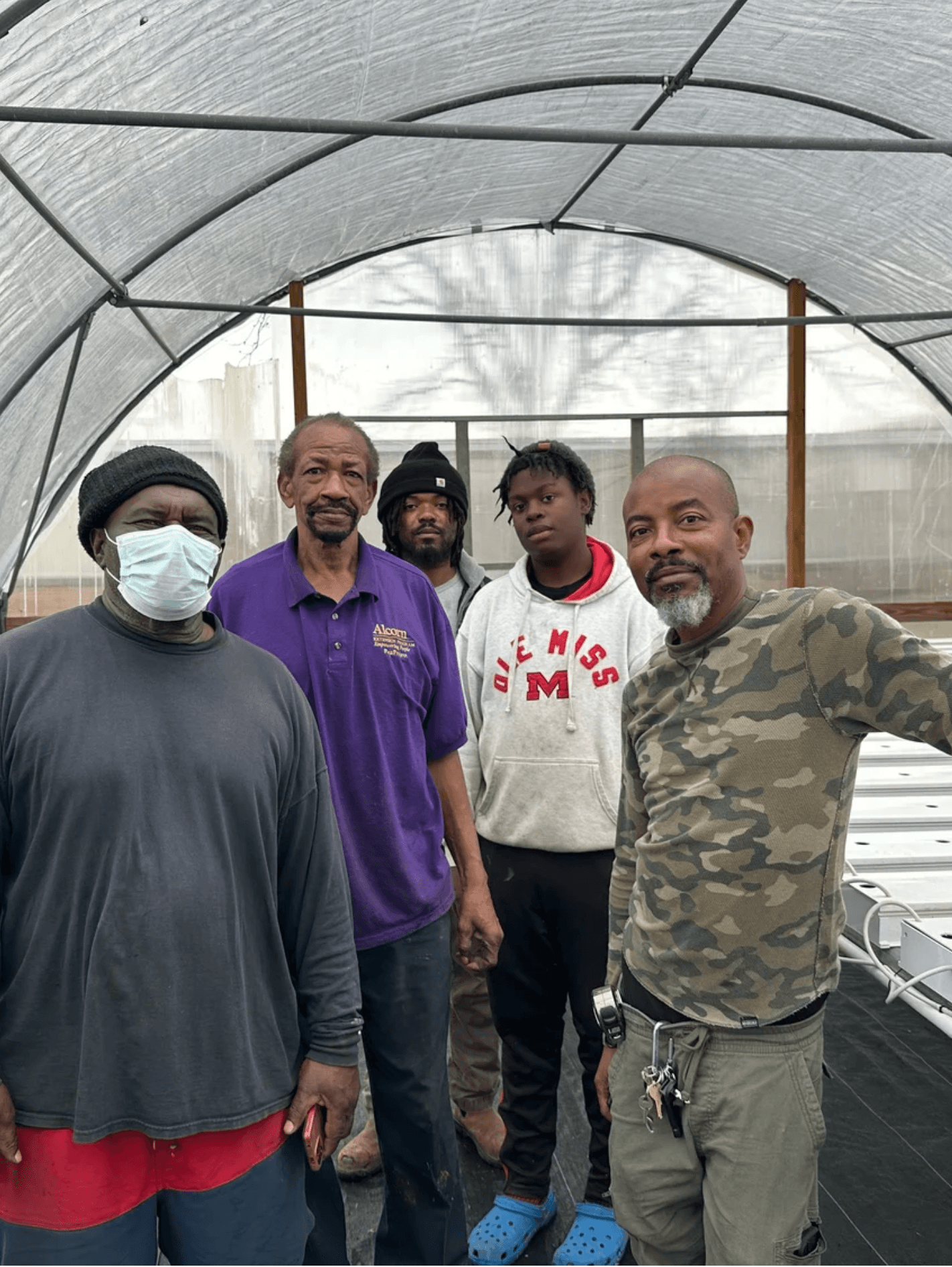 Delta Grows participants standing together inside a community hoop house